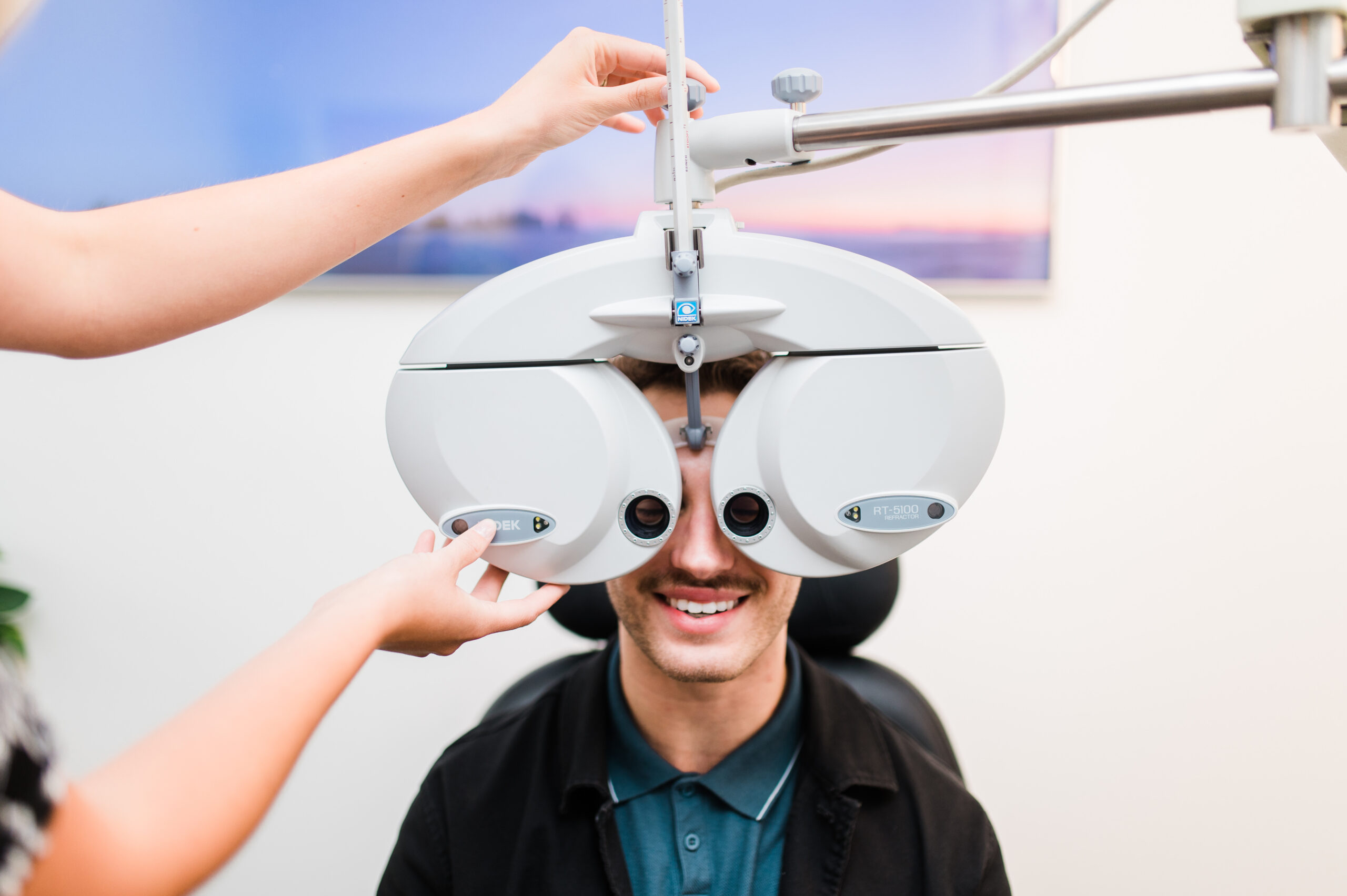 A young man shows how patients are tested for degenerative diseases in an eye care clinic