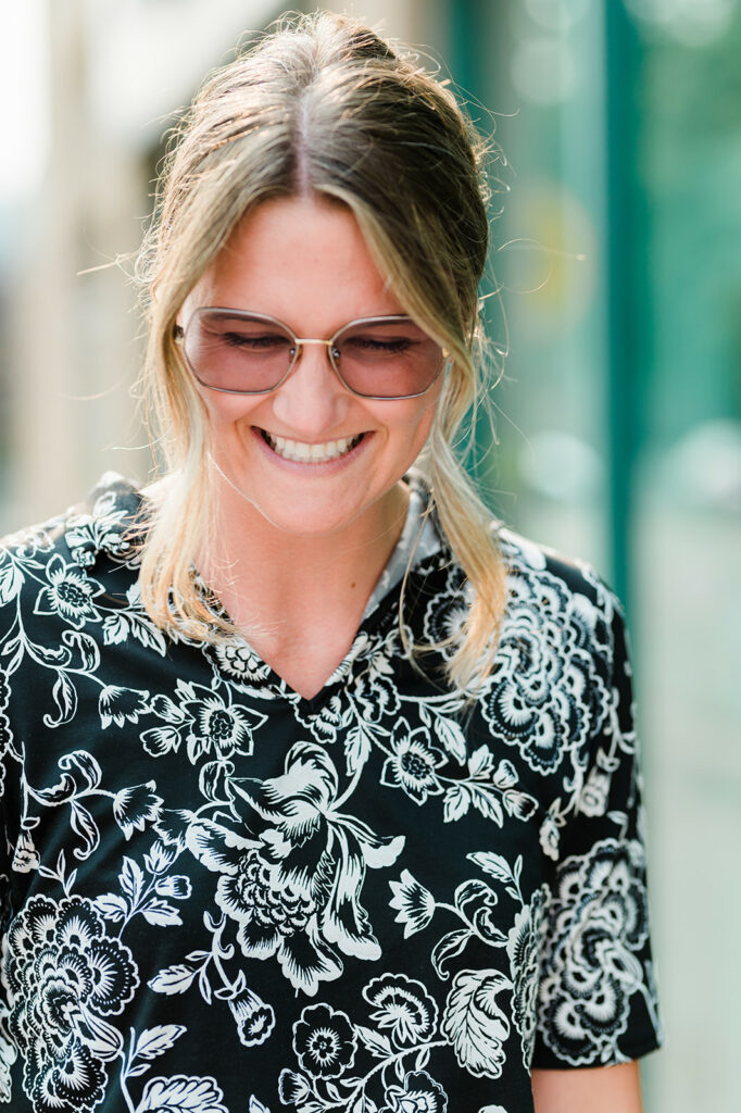 A woman smiles standing outside as her transition lenses adjust to the outdoor lighting