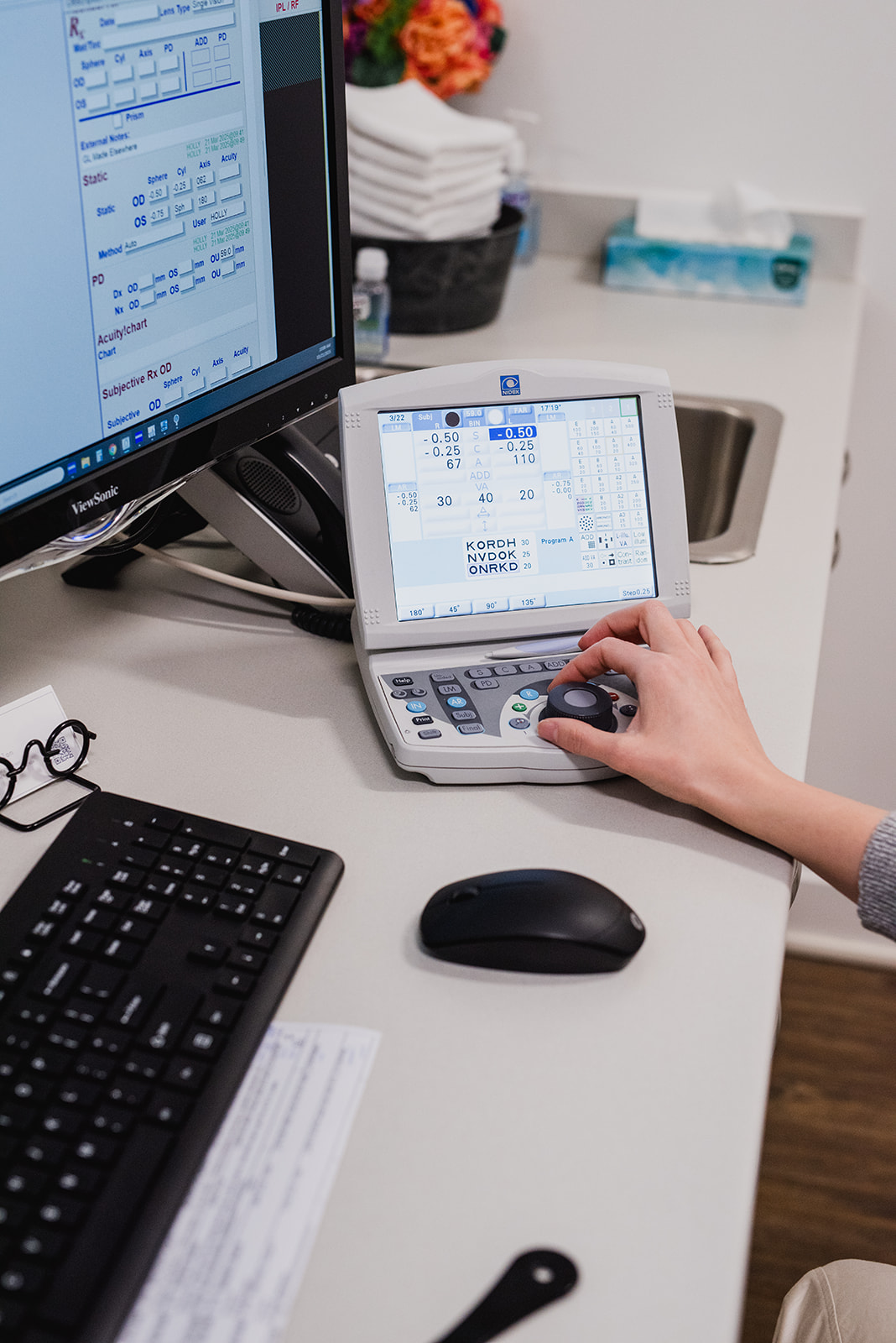 Close-up of advanced eye care treatment equipment with a touchscreen display and handheld device used for in-office eye and skin treatments.