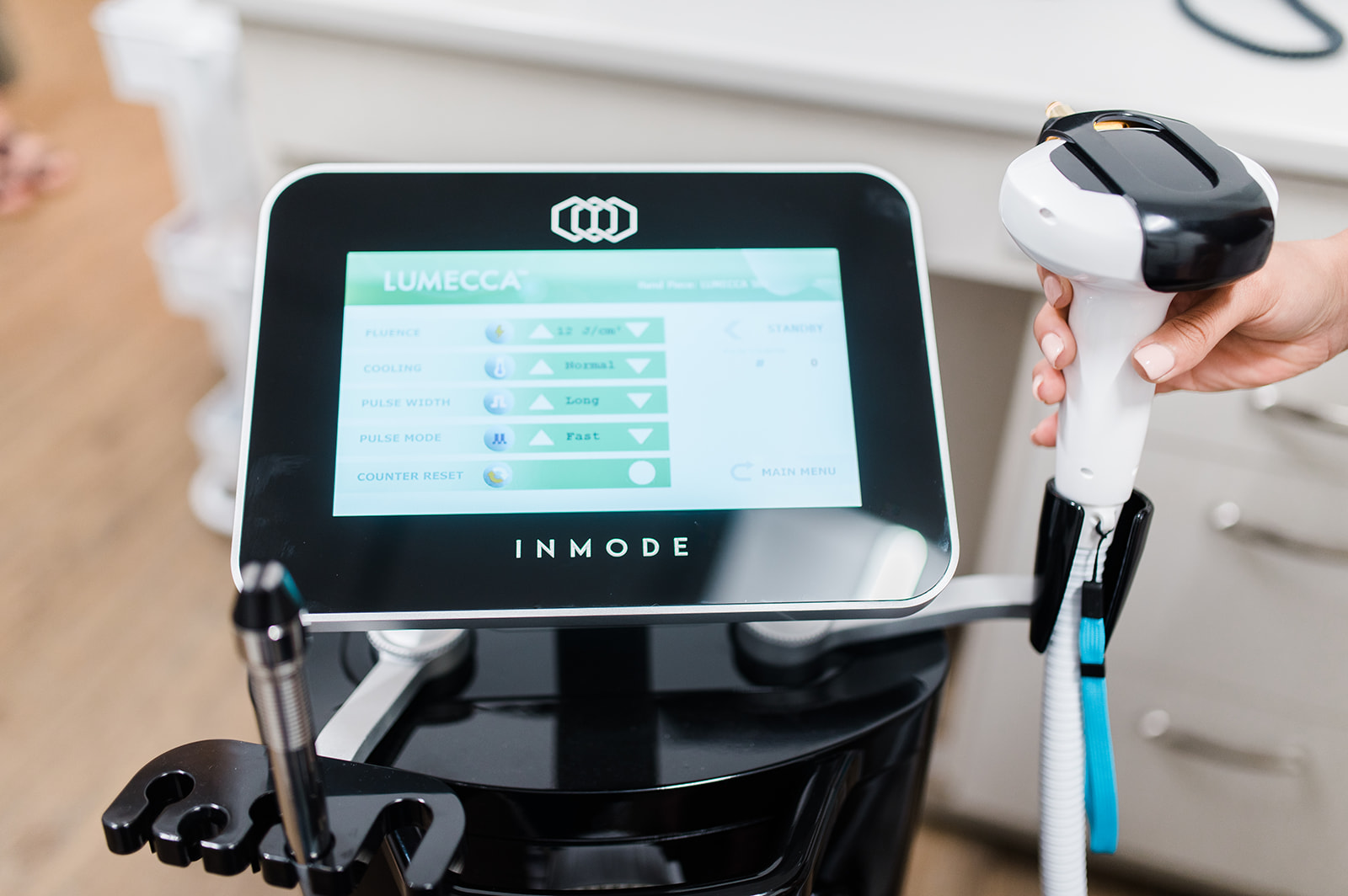 Close-up of advanced eye care treatment equipment with a touchscreen display and handheld device used for in-office eye and skin treatments.